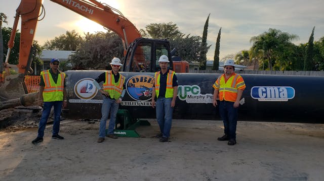 The design built team poses with the force main pipe at the construction site in Fort Lauderdale.