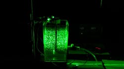 Researchers used a green laser on a jar filled with water to show how the water moves and how contaminants clump together. Researchers used a green laser on a jar filled with water to show how the water moves and how contaminants clump together.