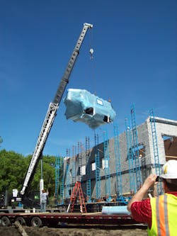Contractors lift a belt filter press into place before the roof installation.
