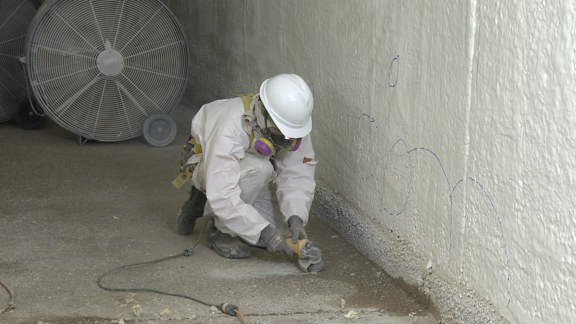 A worker prepares a concrete surface for a rehabilitation project at a wastewater treatment plant.