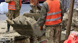 City workers repair a sewer line under a public roadway