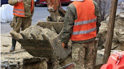 City workers repair a sewer line under a public roadway