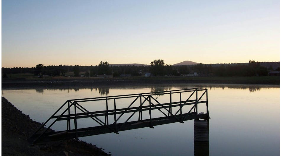 A catwalk over a wastewater treatment lagoon at sunset.