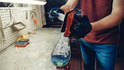 A man uses an iron to apply ski wax to a ski. A man uses an iron to apply ski wax to a ski.