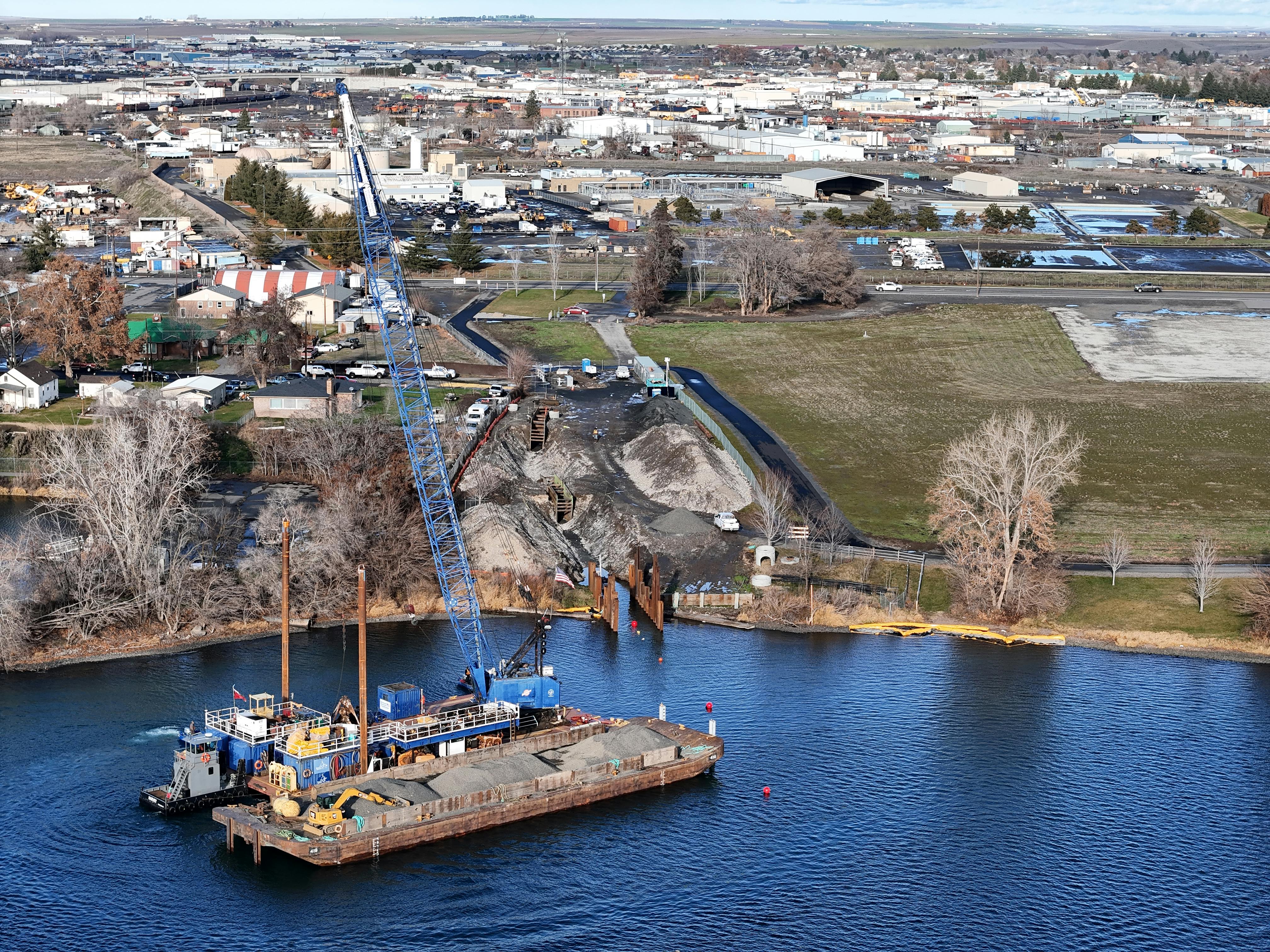 A crane floats on a barge during construction of the Pasco, Washington wastewater treatment plant.