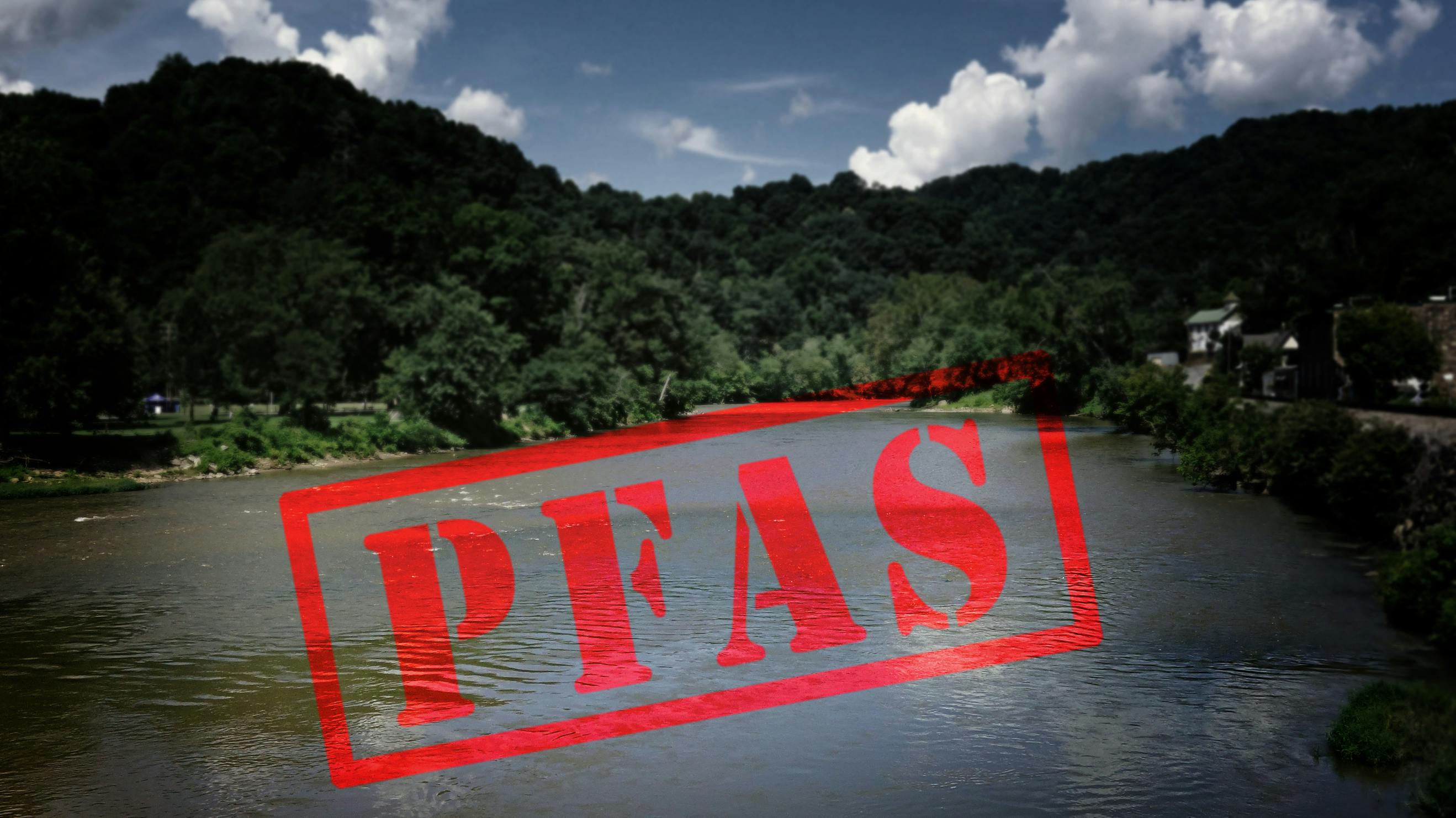 Red PFAS ( Forever Chemicals ) stamp with a river in the background